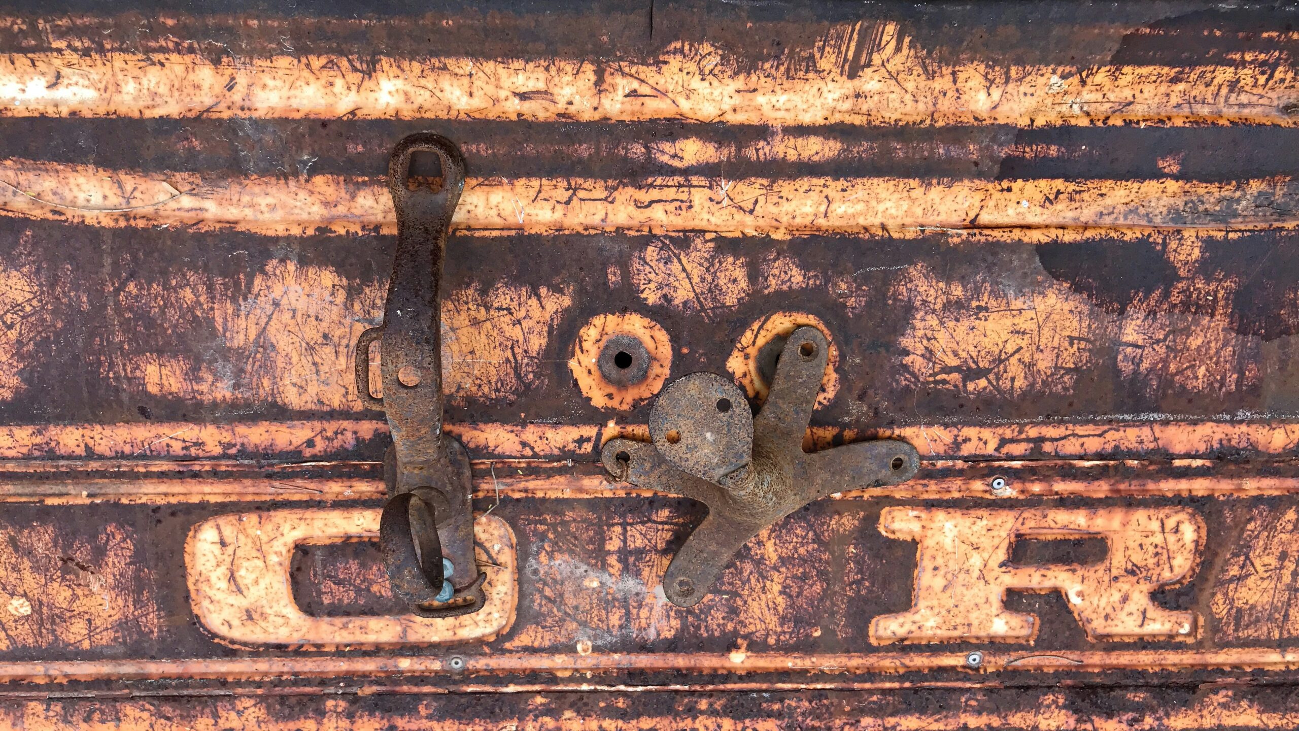 A broken non-TSA-approved lock lying next to a hardshell suitcase