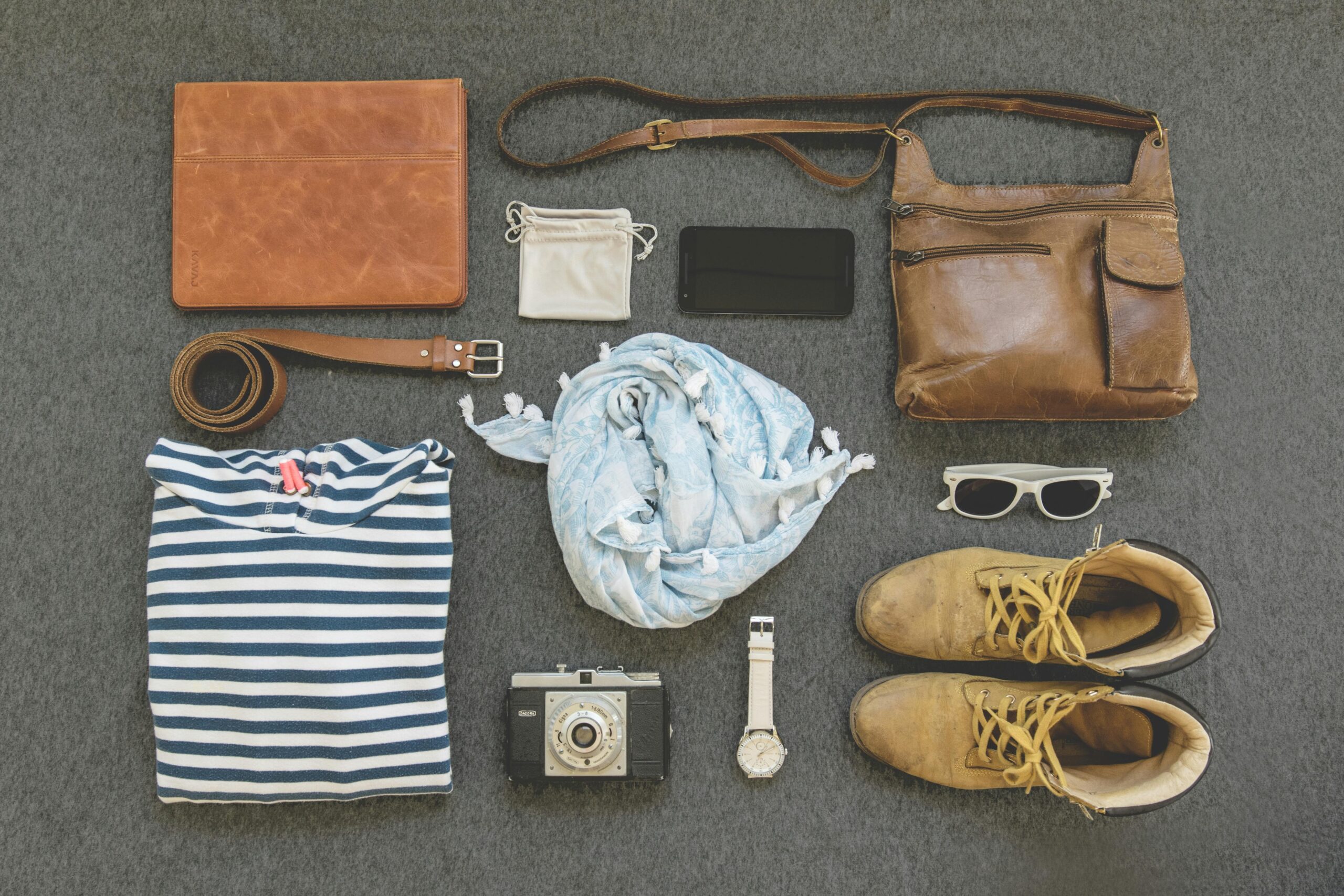 A sleek black hardshell suitcase next to airplane boarding pass and sunglasses