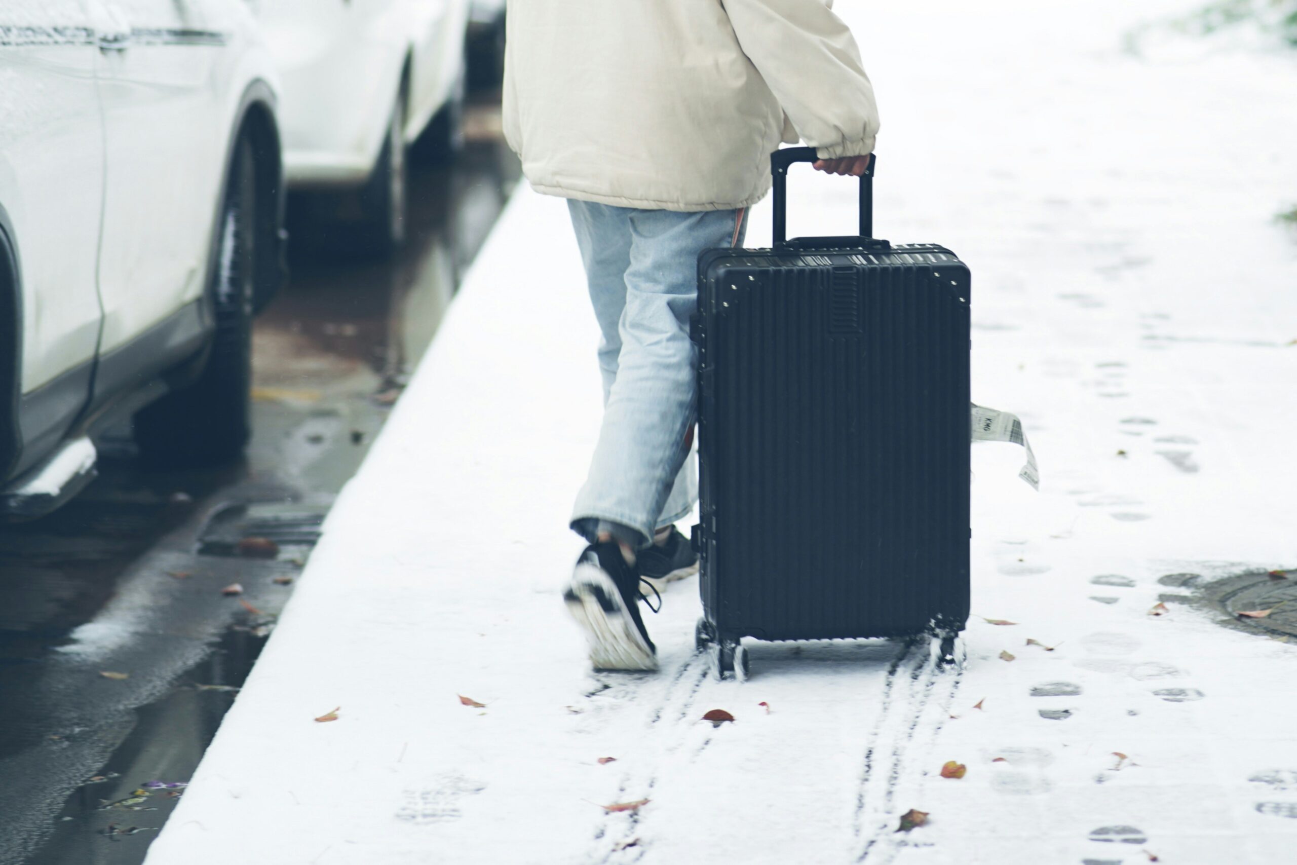 Photograph of happy traveler posing next to compact carry-on suitcase