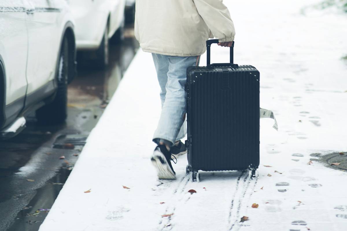 A traveler smiling next to her durable polycarbonate suitcase in an airport